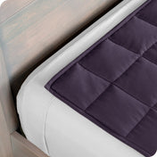 Close up of a weighted blanket on top of a bed made with white sheets