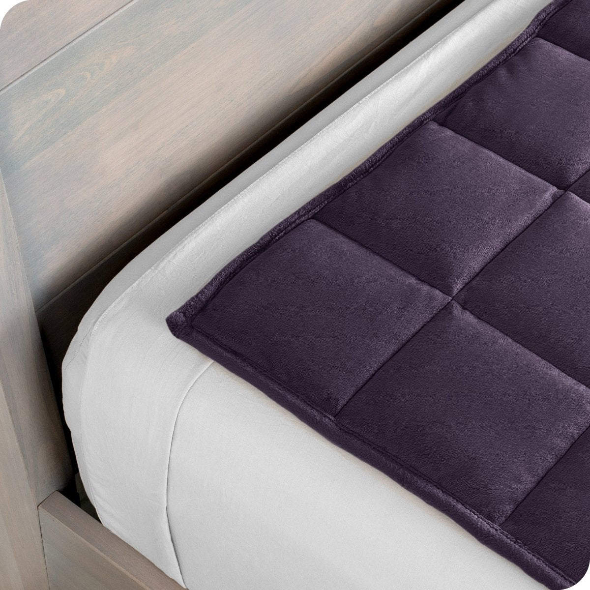 Close up of a weighted blanket on top of a bed made with white sheets