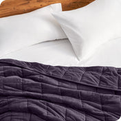 Close up of a weighted blanket on a bed next to pillows