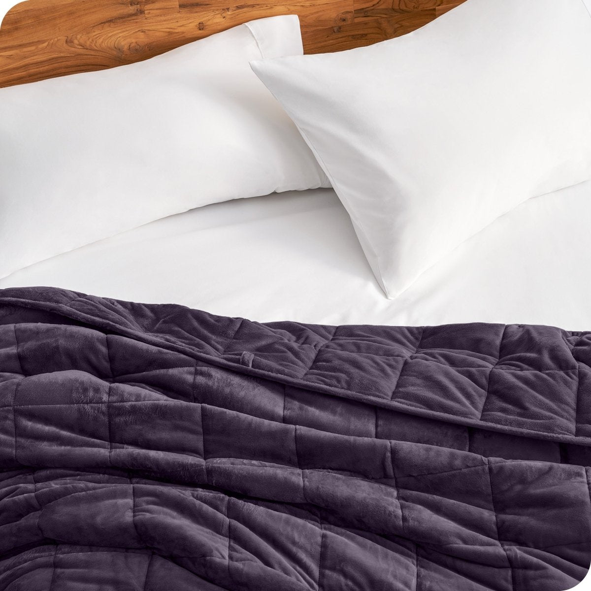 Close up of a weighted blanket on a bed next to pillows