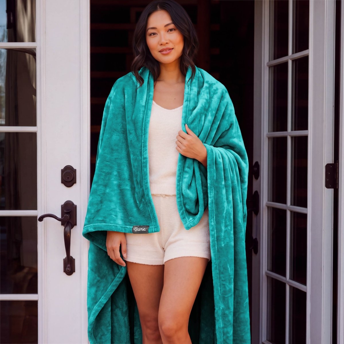 A woman standing with a microplush blanket wrapped around her