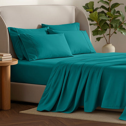 Bed sheets and pillows on a bed with a plant and side table in the background.