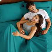 A couple is relaxing in bed with pillows behind them