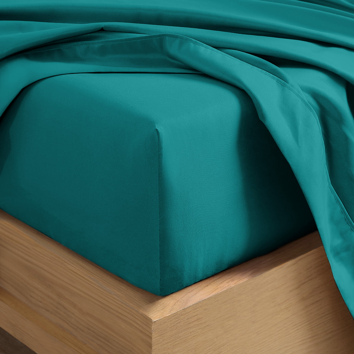 Close up of the corner of a mattress with a fitted sheet and flat sheet on it