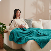 A woman sitting on a couch with a microplush blanket on her