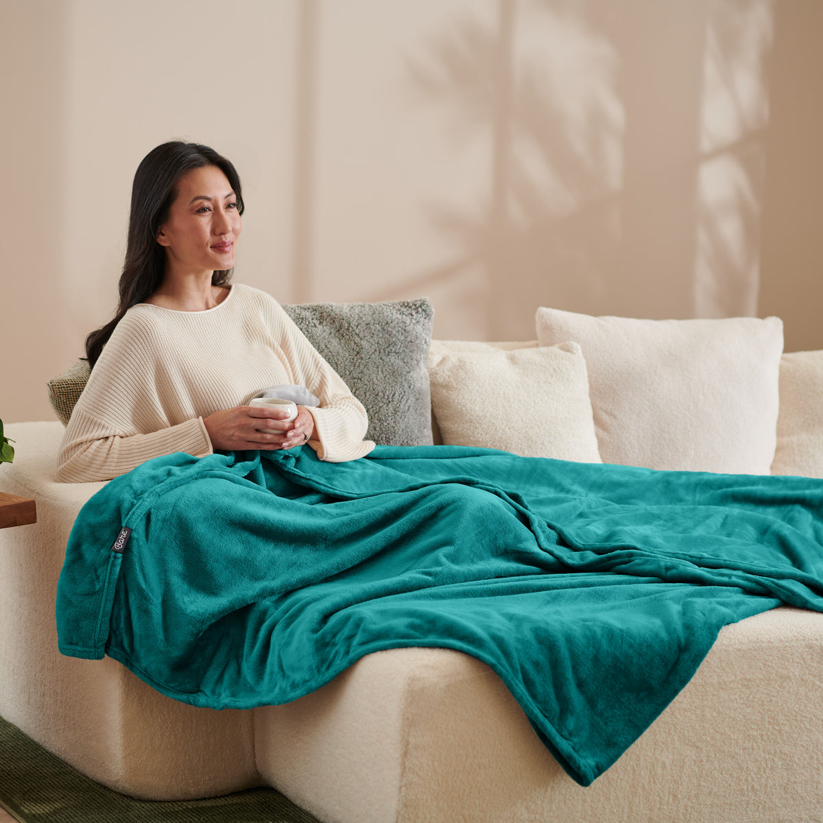 A woman sitting on a couch with a microplush blanket on her lap