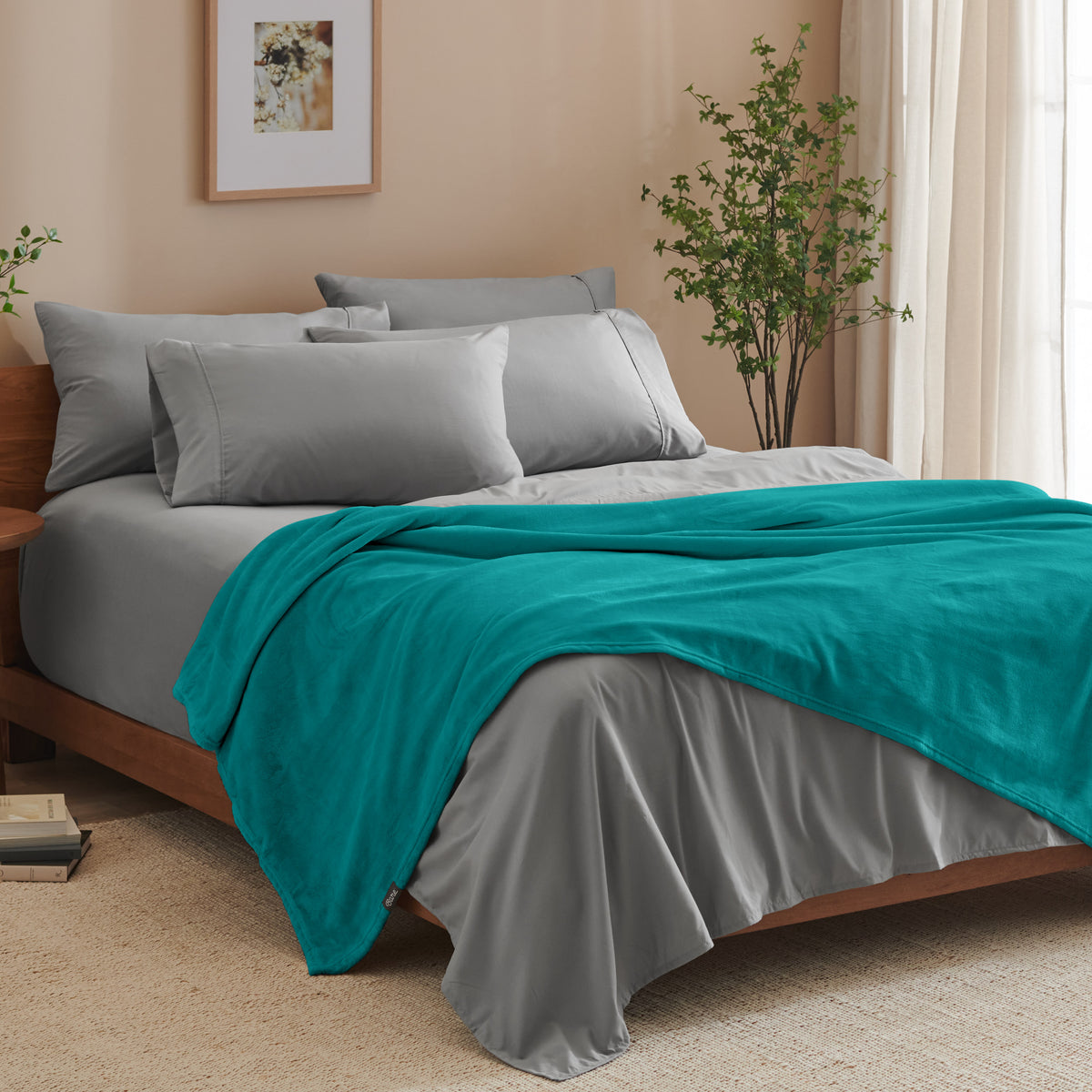 A bed made with grey sheets and a microplush blanket