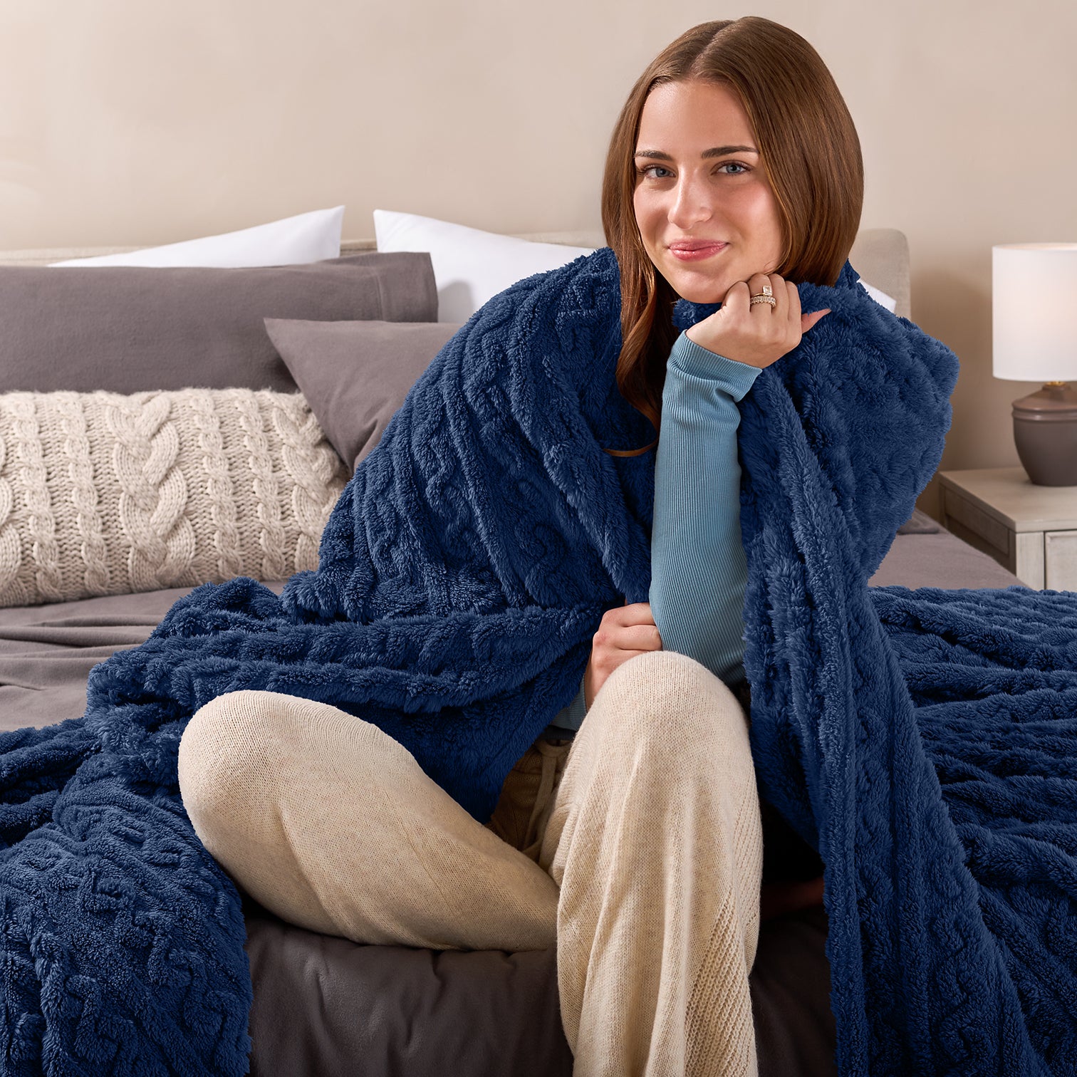 Woman with a blue cable knot blanket wrapped around her