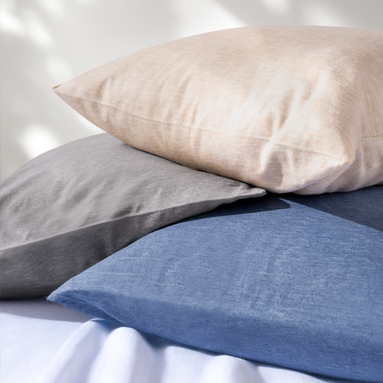 Three pillows in beige, gray, and blue on a white background