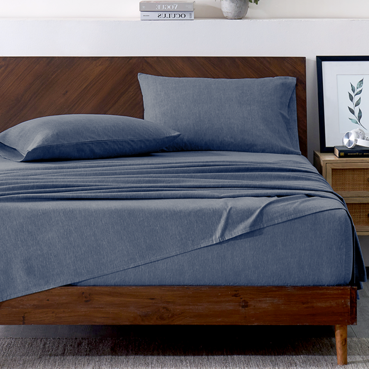 Blue bedding set on a wooden bed with a wooden headboard and nightstand.