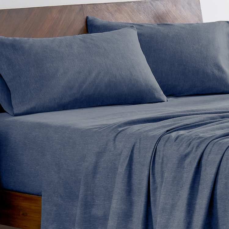 Blue bed sheets and pillows on a wooden bed frame