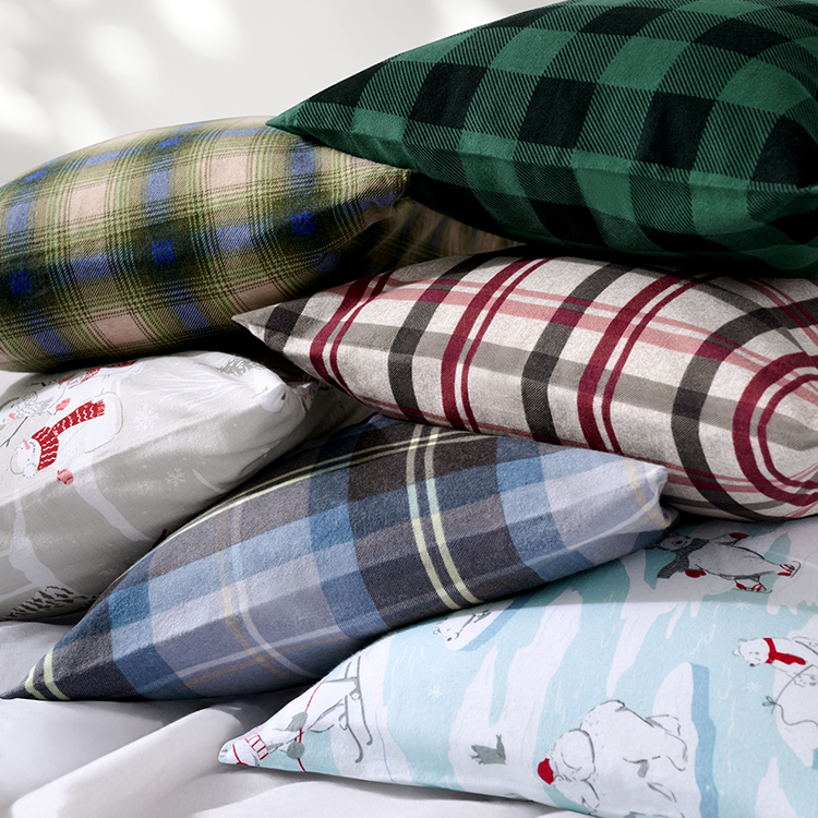 Stack of plaid and patterned pillows on a bed