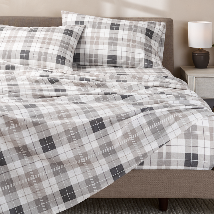 Plaid patterned bedspread on a bed with matching pillows in a bedroom setting.
