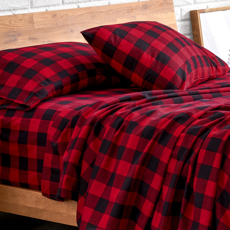 Red and black checkered bedding set on a wooden bed frame.