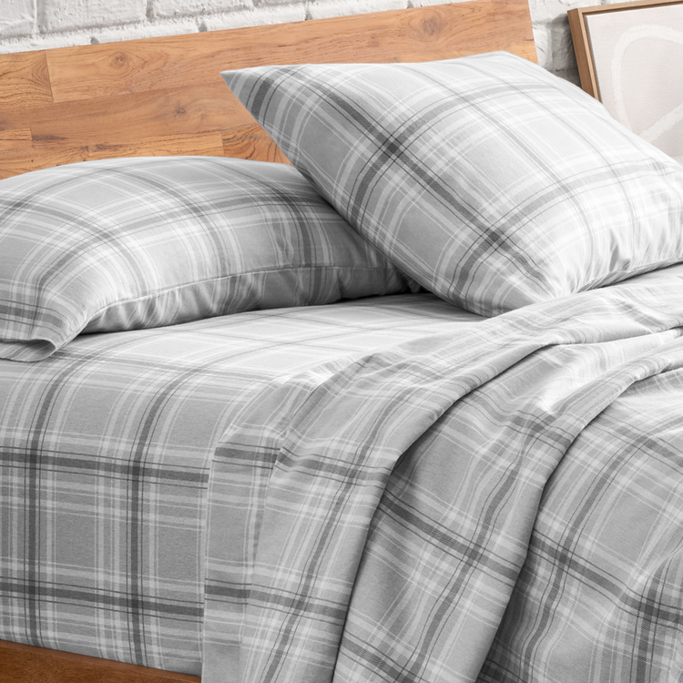 Gray plaid bedding set on a bed with wooden headboard