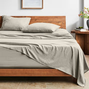 Bed with washed sheets and wooden headboard in a room setting.