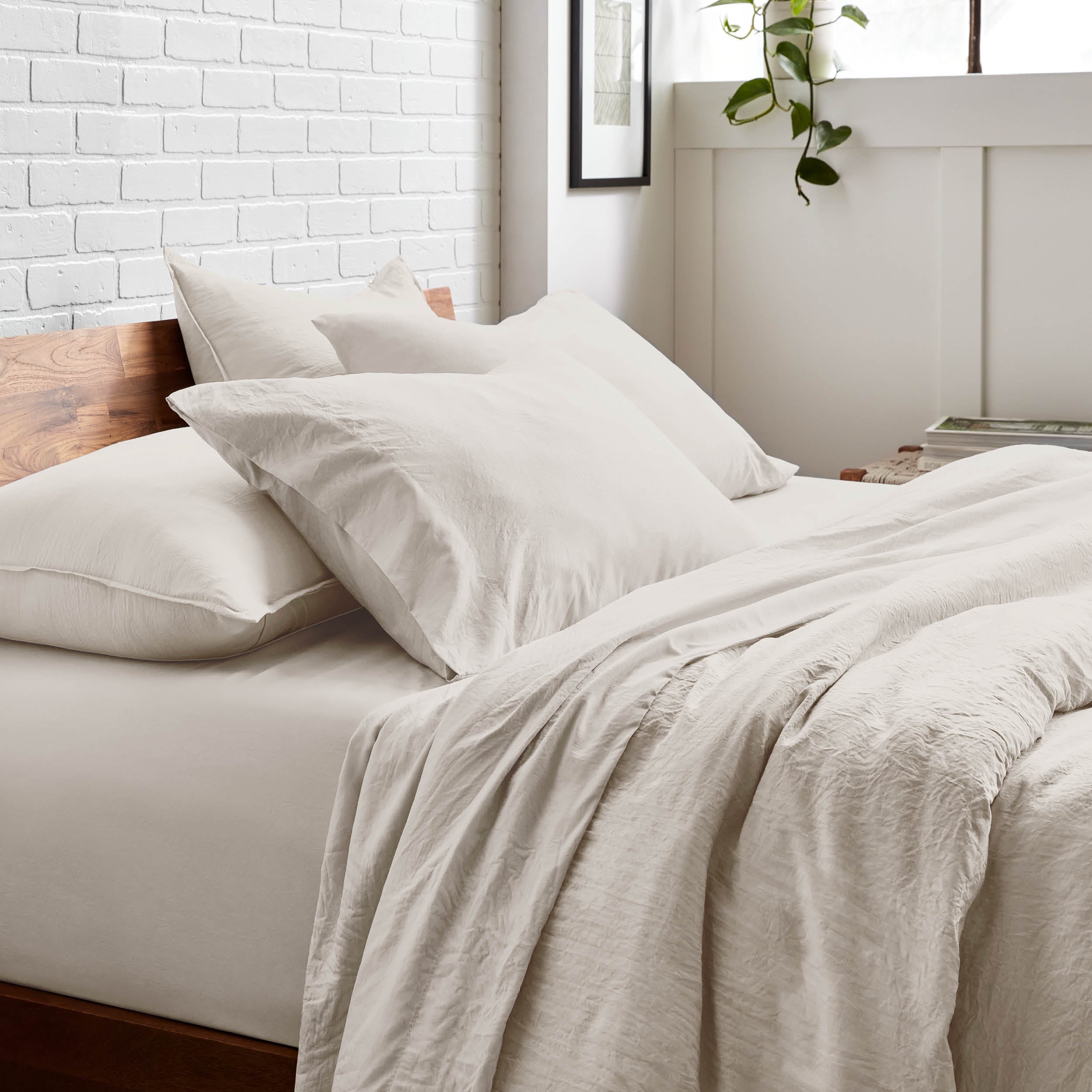 Bedding set on a bed with a white brick wall and window in the background