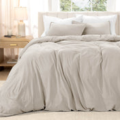 Bed with washed bedding and white pillows in a bright room