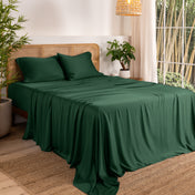 Bamboo sheets on a bed in a bedroom with plants and a lamp.
