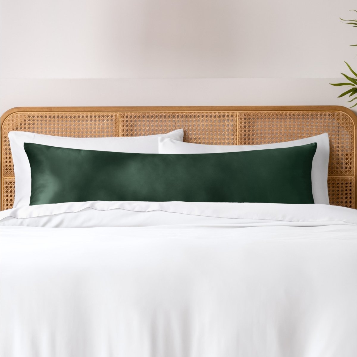 Pillows, sheets and a duvet cover on a bed with a wicker headboard and light gray bedding.