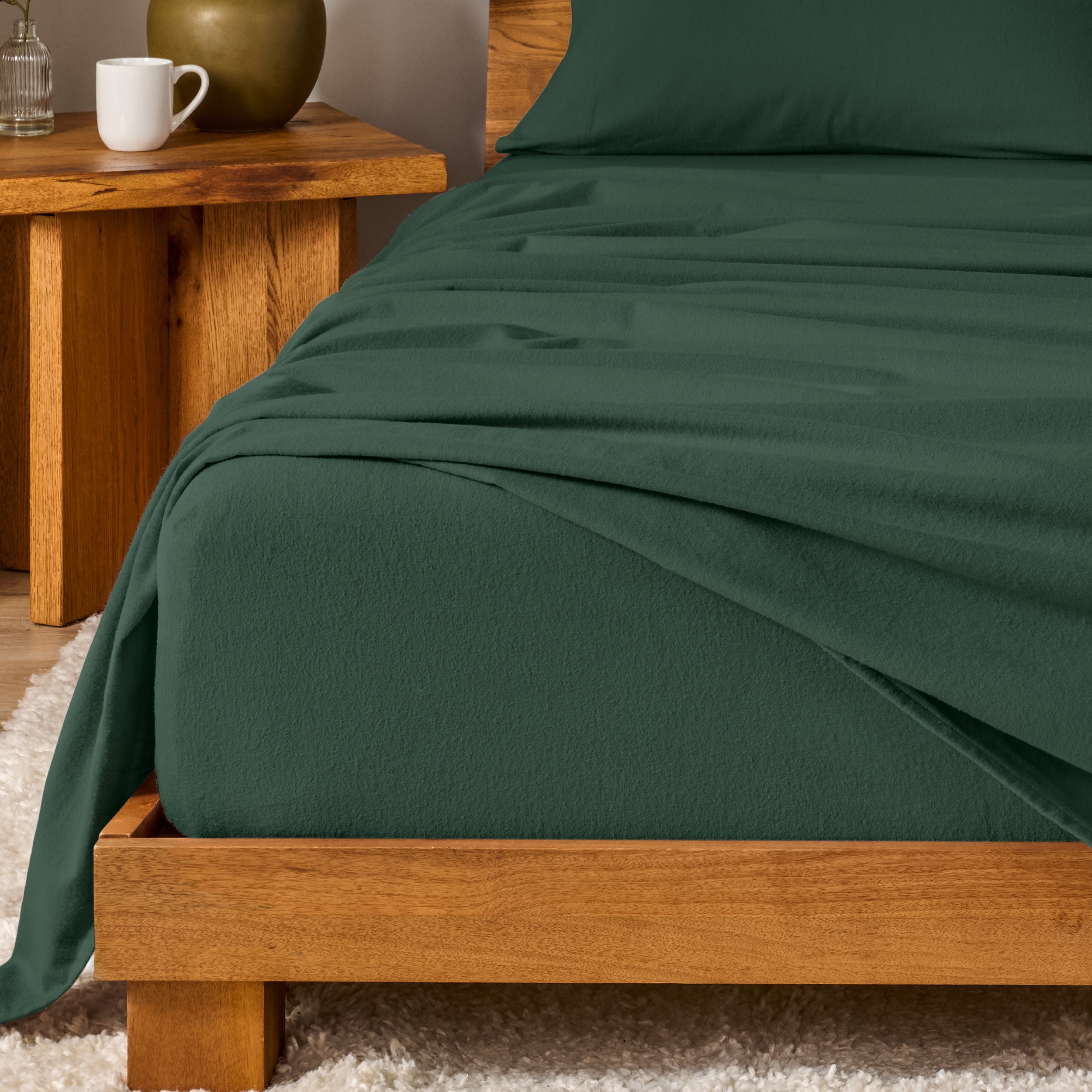 Bed with flannel bedding and wooden headboard and nightstand next to it.