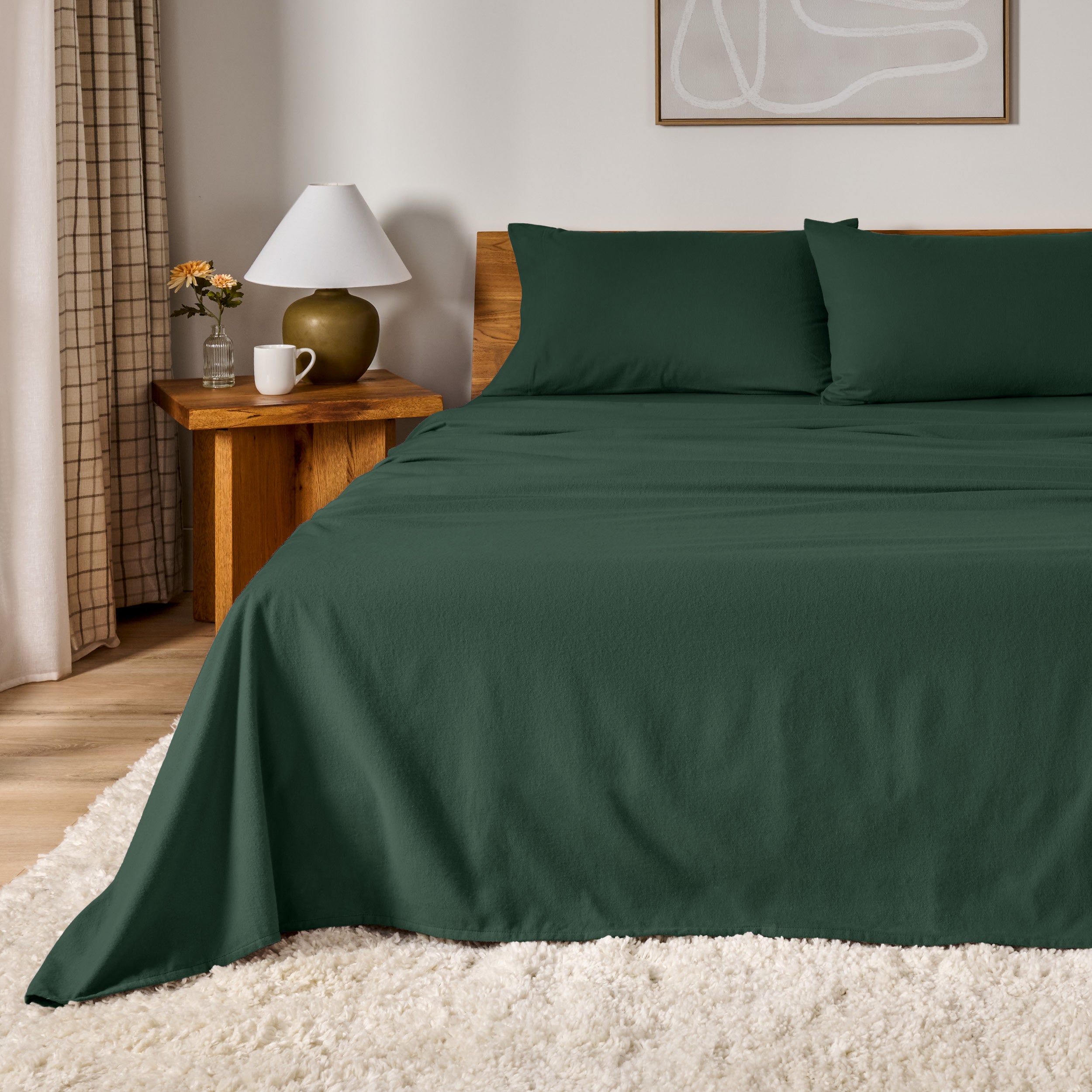 A bed dressed in flannel sheet set in a bedroom with a wooden headboard, bedside table and lamp