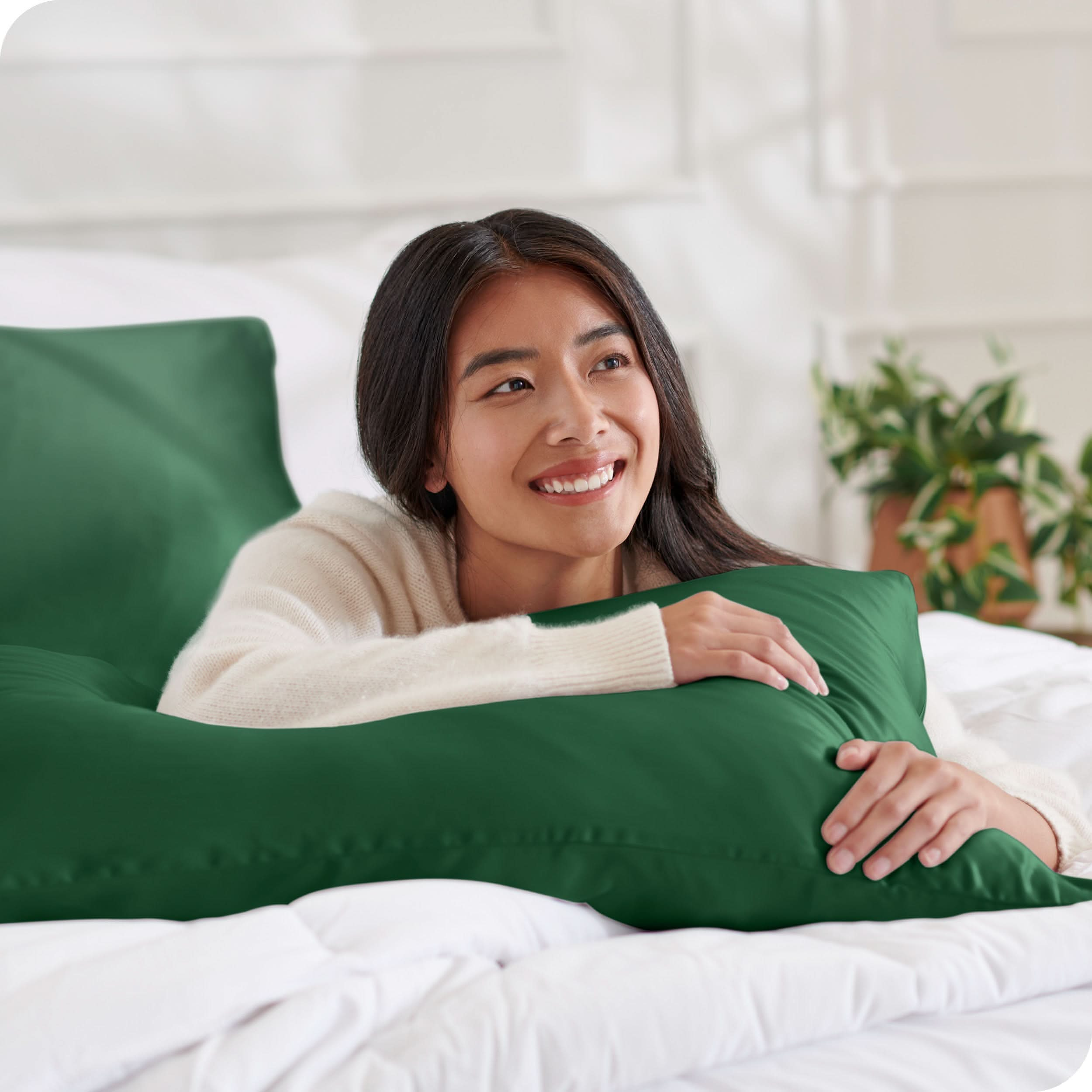 A woman on a bed with a silk pillowcase covered pillow