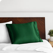 A green silk pillowcase on a pillow resting on a headboard