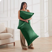 A woman standing while holding pillows with silk pillowcases on them