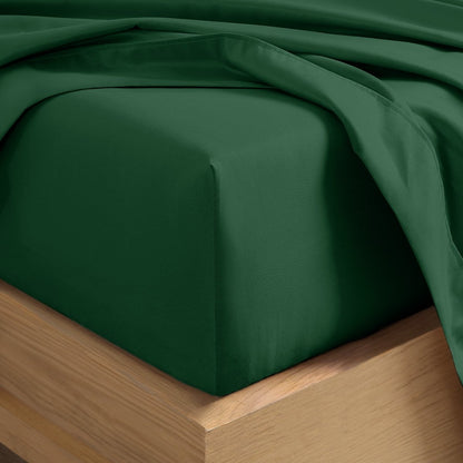 A close-up of a fitted sheet covering the corner of a bed frame, with matching top sheet draped over it.