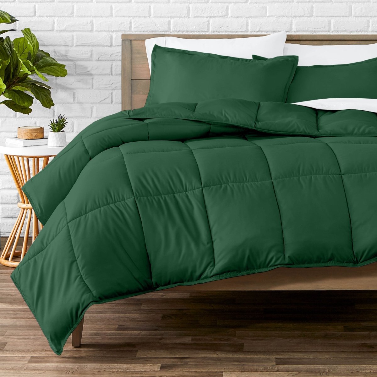 Comforter set on a bed with a white brick wall and plant in the background