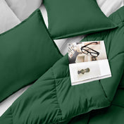 Comforter and pillows on a bed with a magazine and glasses.