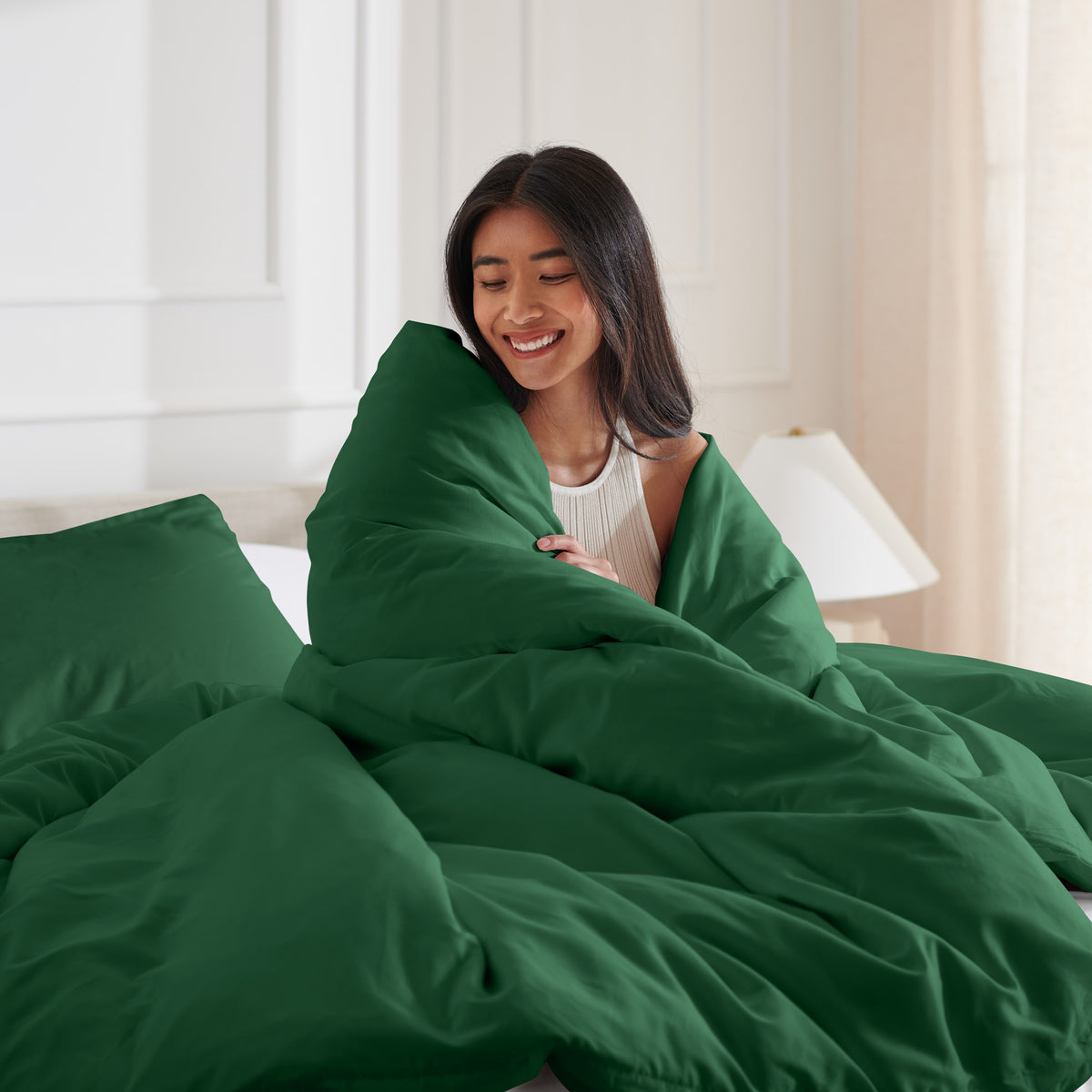 Woman smiling under duvet cover set in a bedroom setting