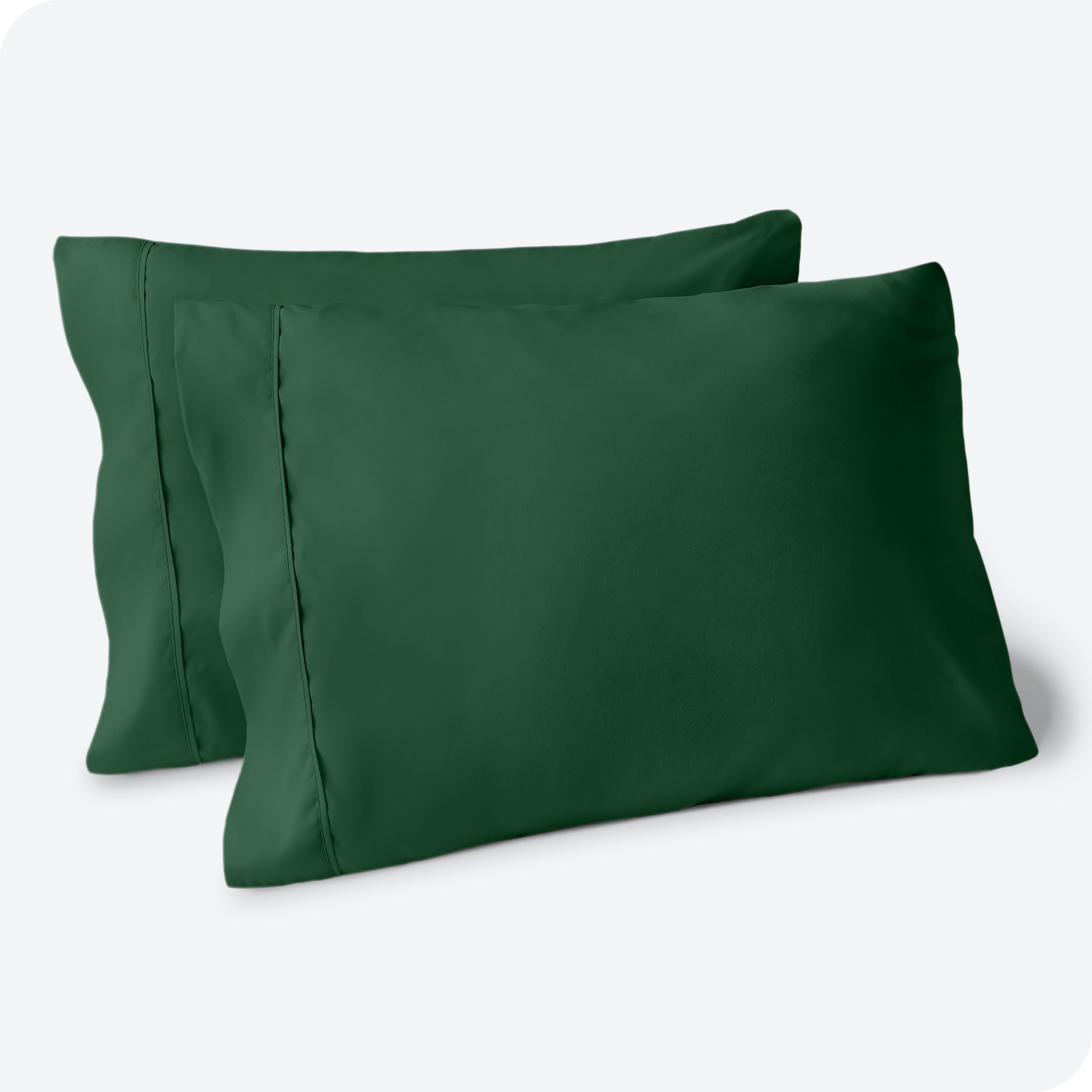 Two pillows on a white background with green pillowcases on them