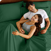 A couple is relaxing in bed with pillows behind them