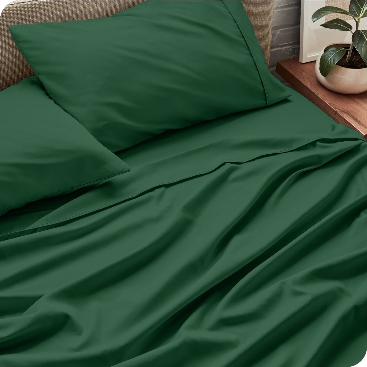Bed sheets and pillows on a bed with a plant in the background