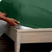 A man is putting a fitted sheet on a mattress