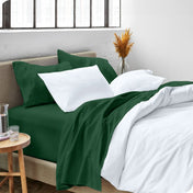 A side view of a bed made with microfiber sheets and a white duvet cover