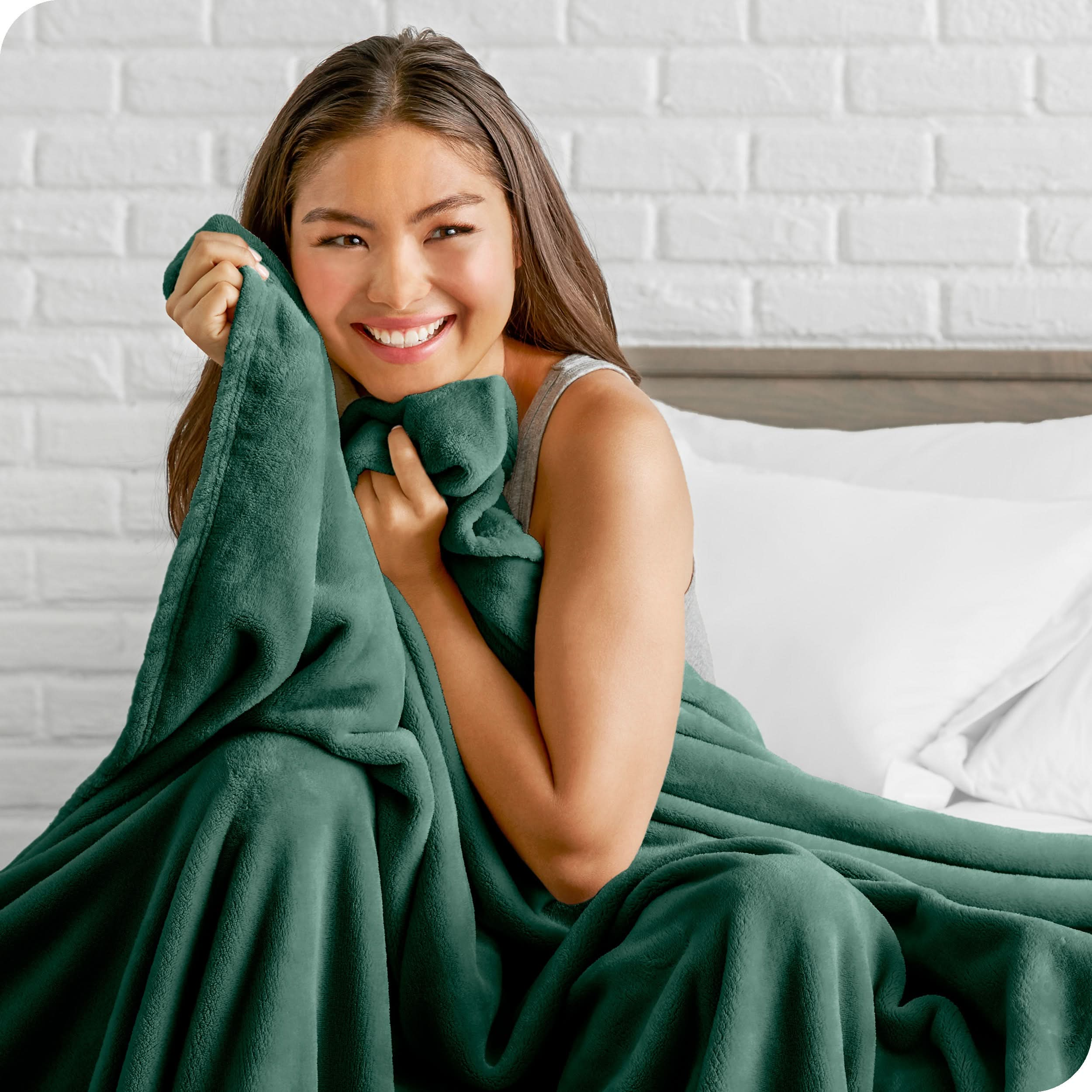 Woman sitting on a bed cuddling with a microplush blanket