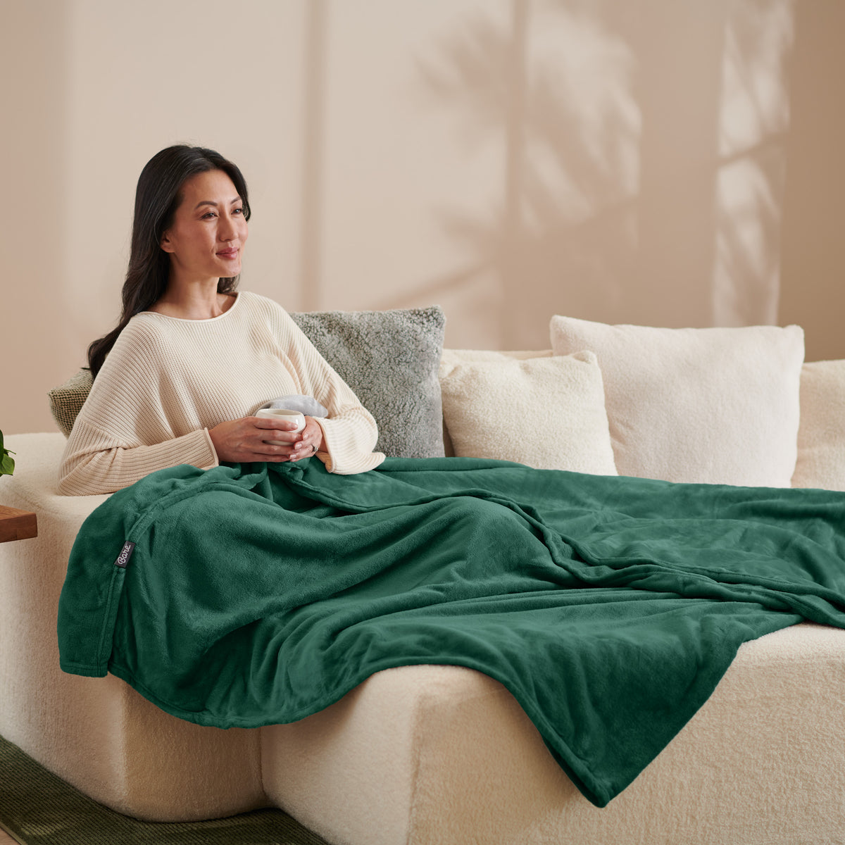 A woman sitting on a couch with a microplush blanket on her lap