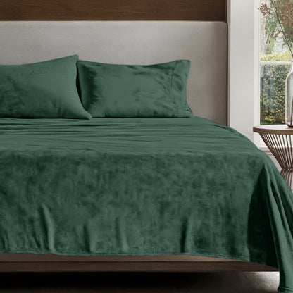 Microplush sheet set on a bed in a bedroom setting with a nightstand and lamp.