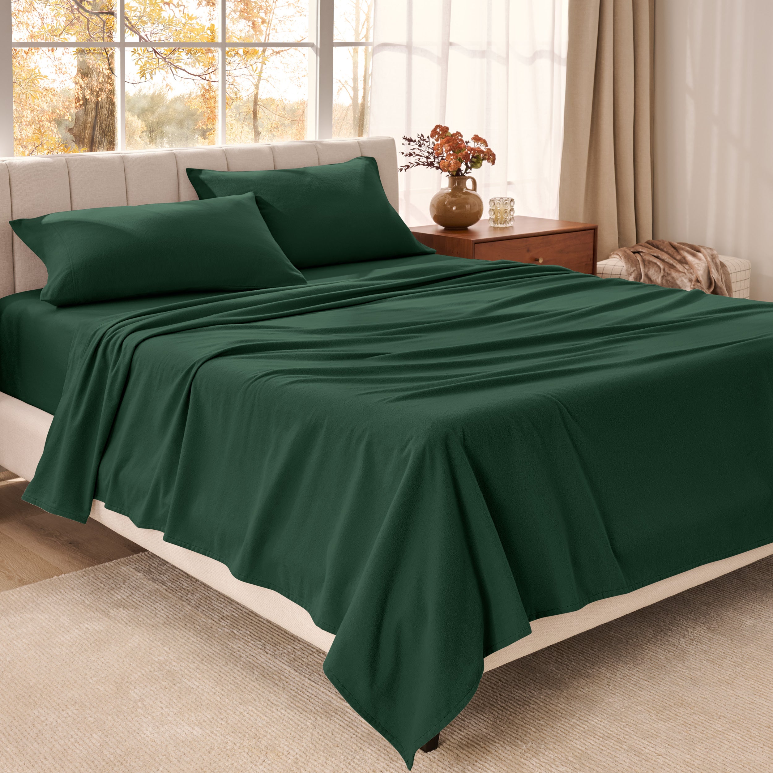 Bed sheets on a neatly made bed in a bright bedroom with large windows.