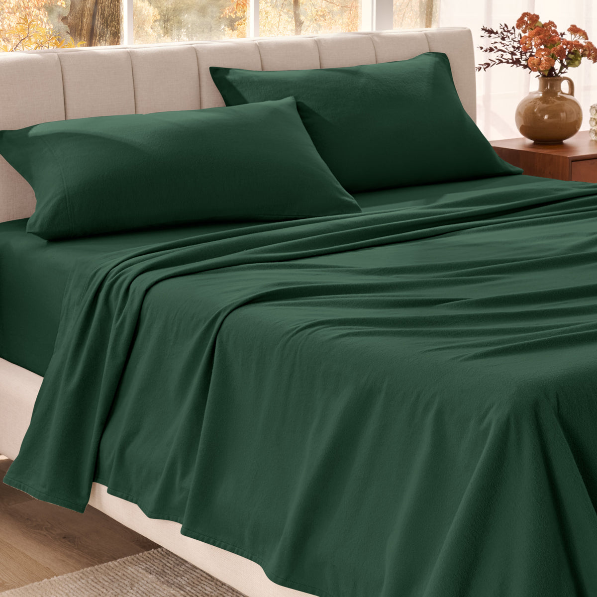 Bed sheets on a neatly made bed in a bright bedroom with large windows.