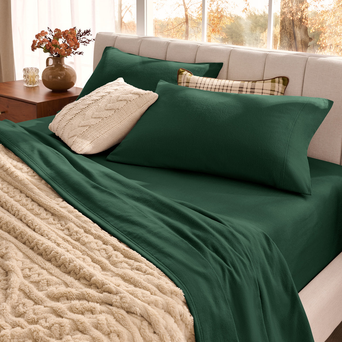 Neatly made bed with organic flannel sheets  and a beige blanket in a bright bedroom.