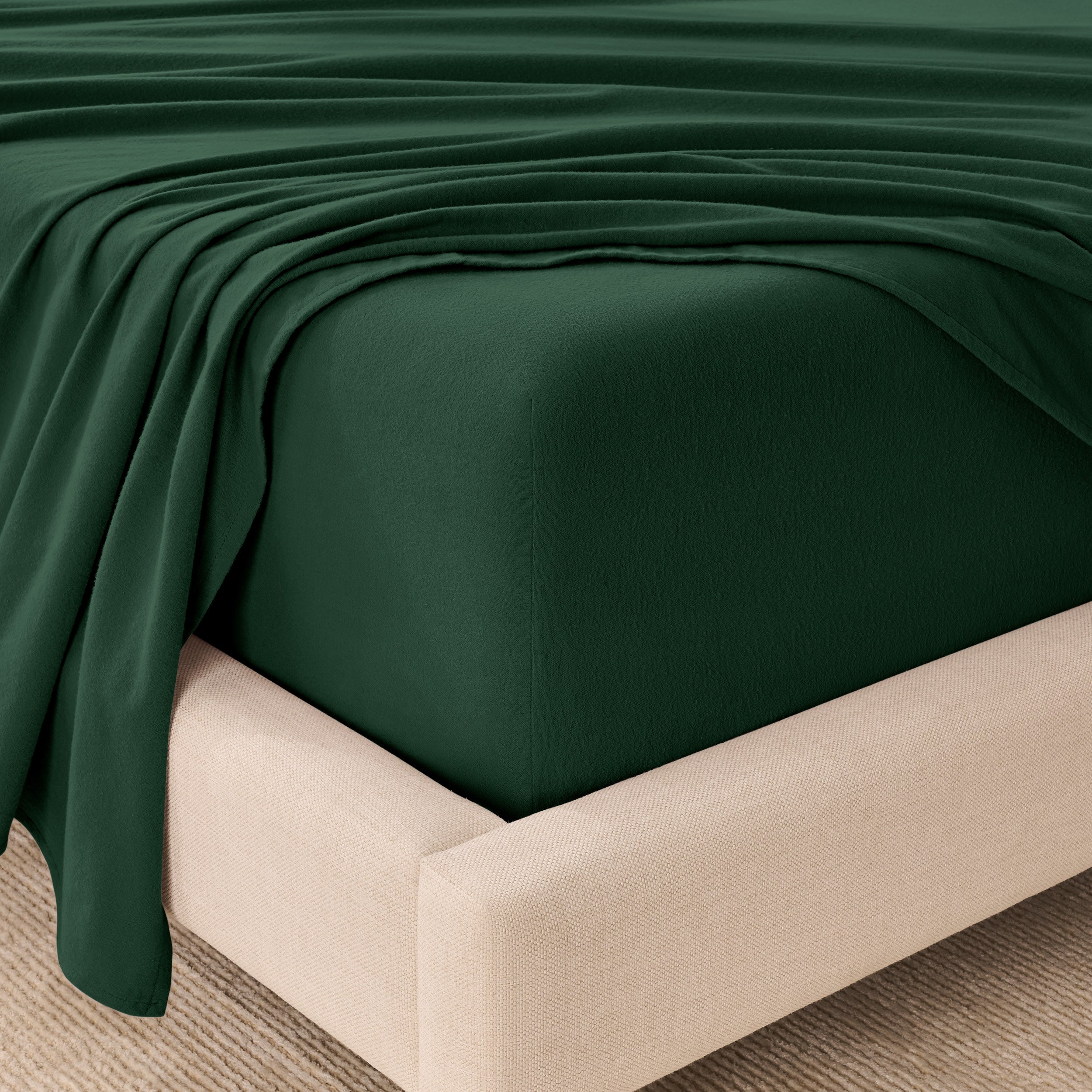 Fitted sheet and top sheet on a mattress with a beige bed frame