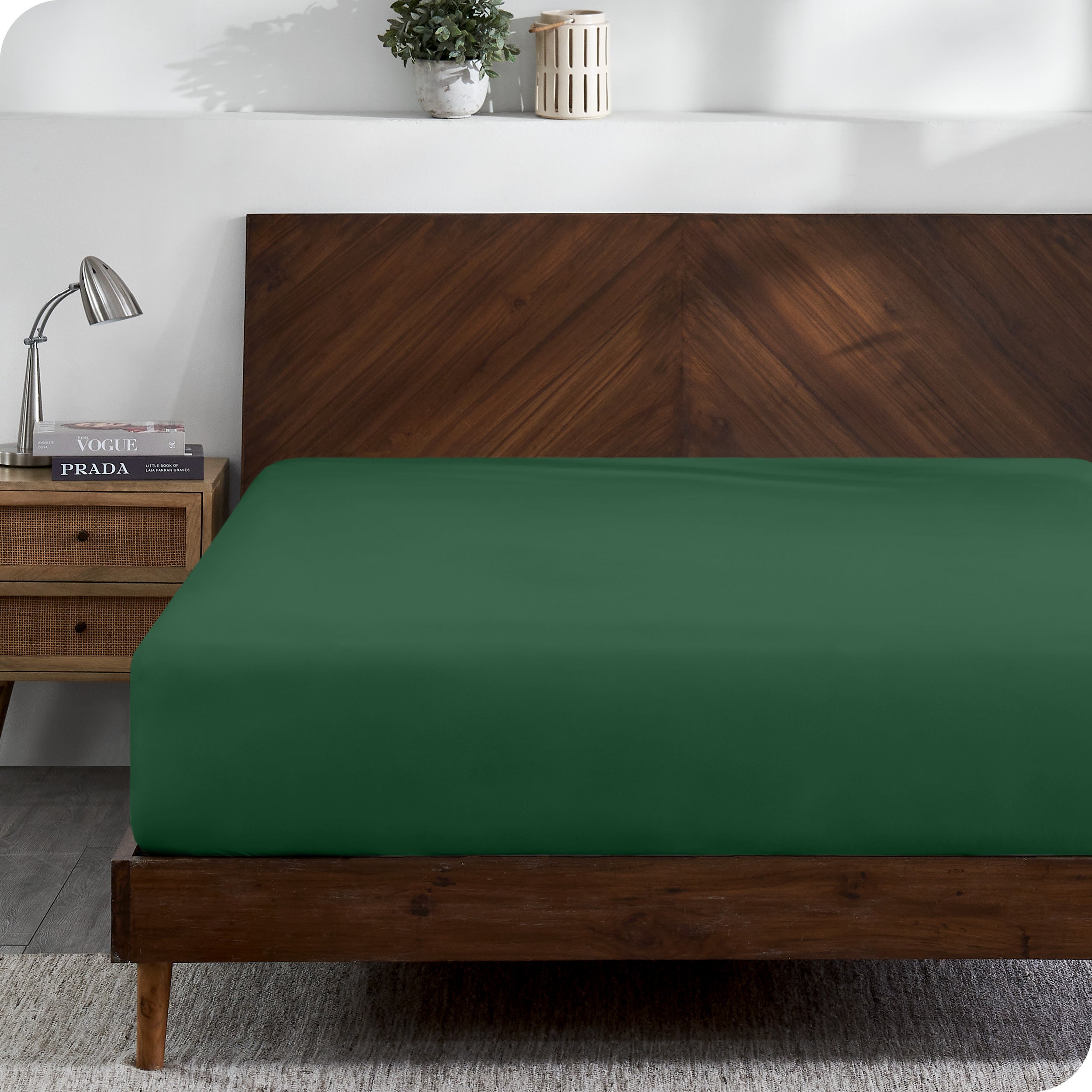 A modern wooden bed frame with a fitted sheet on the mattress