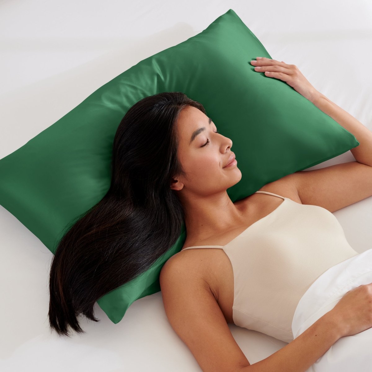 Woman lying on a bed with a pillow covered with a satin pillowcase