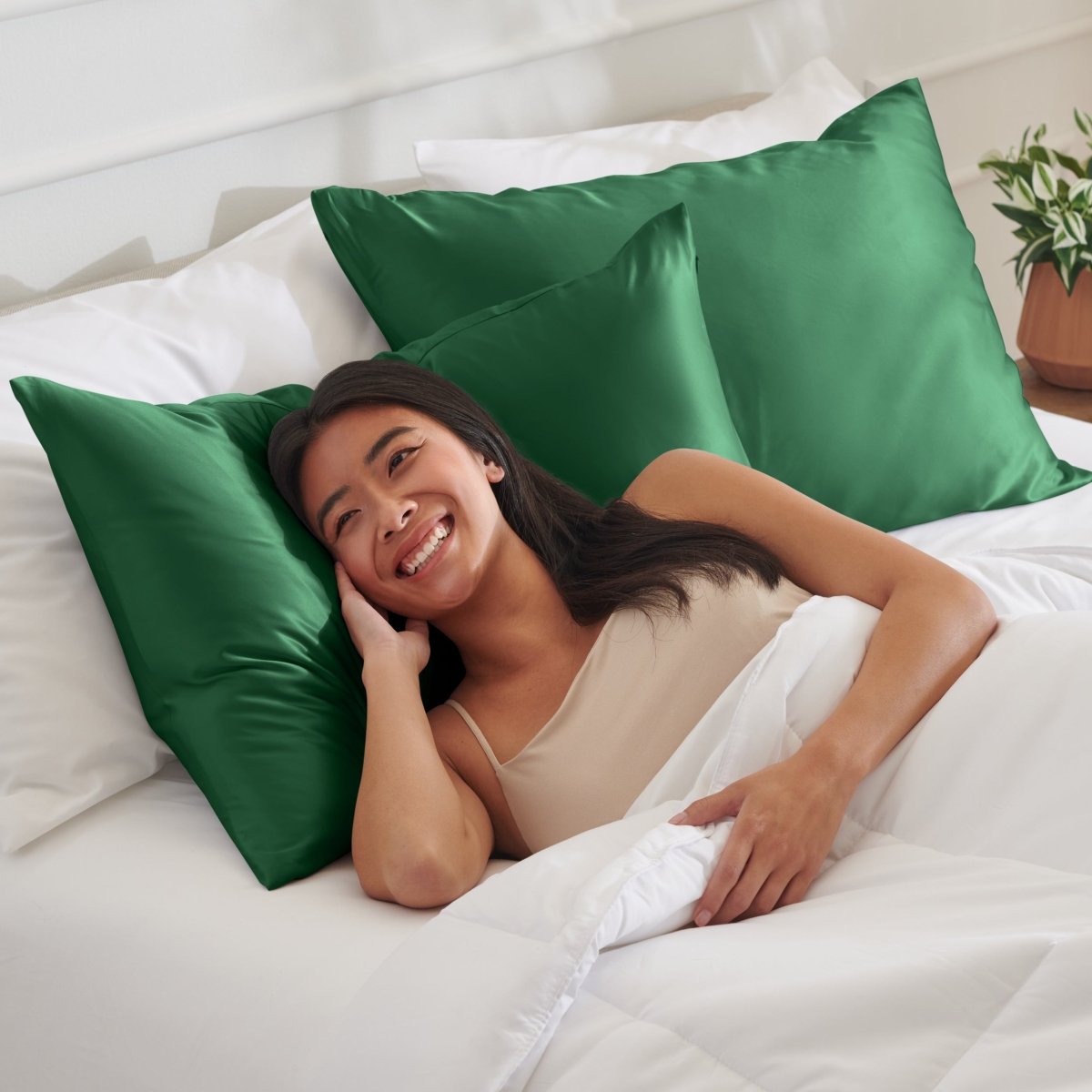 Woman lying on a bed with satin pillows and white bedding