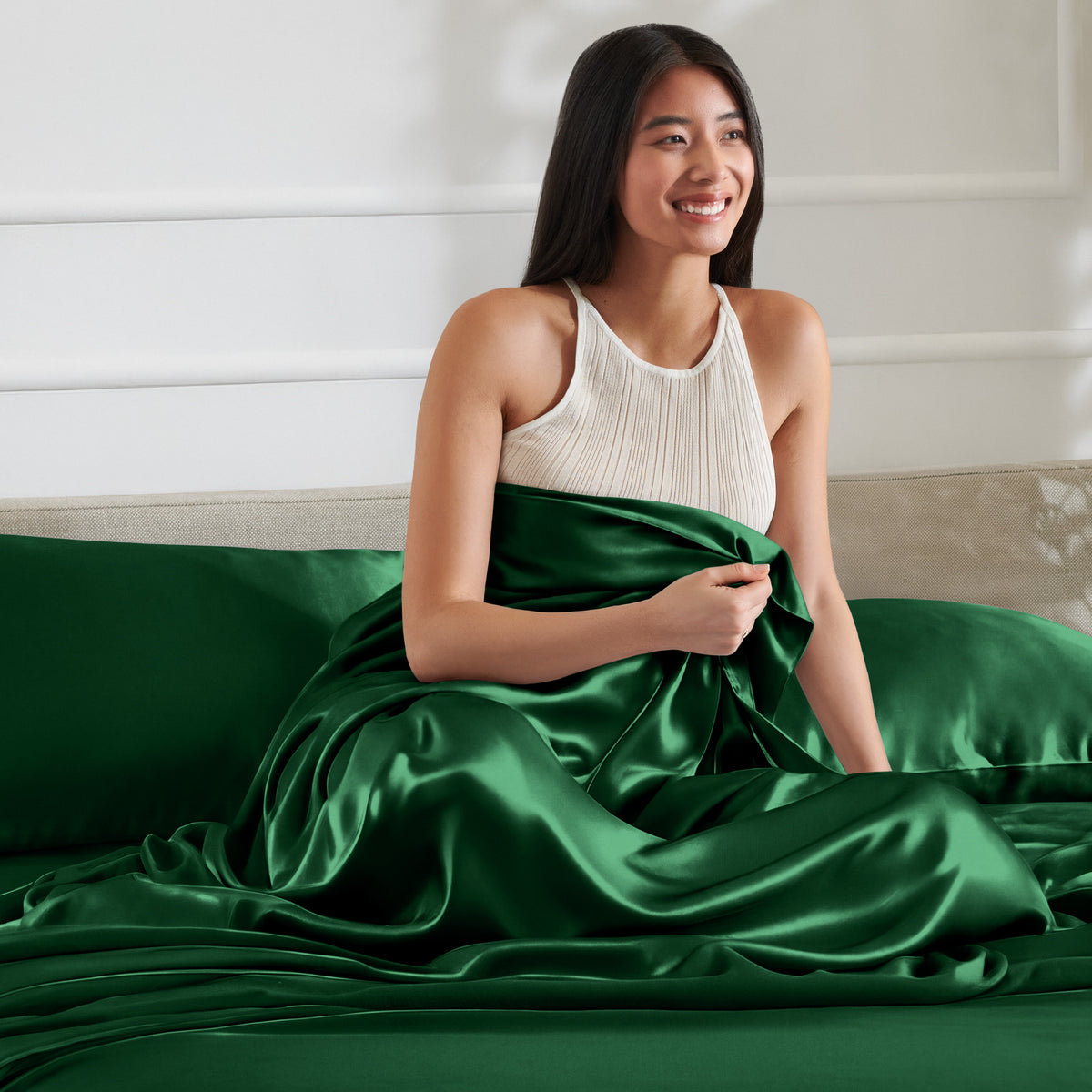 Woman sitting on a bed with satin sheets