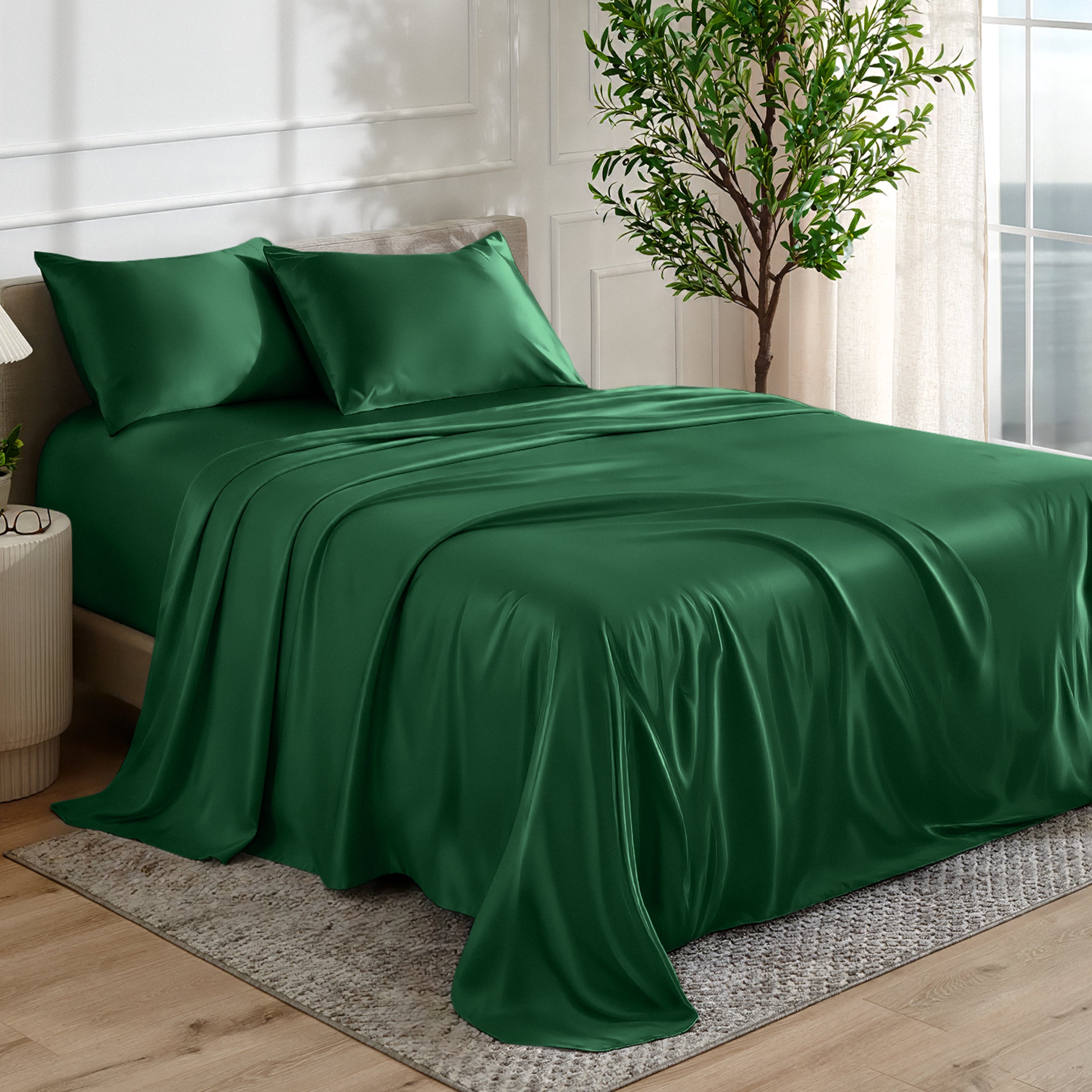 Satin sheet set on a bed in a bedroom with a plant and window in the background.